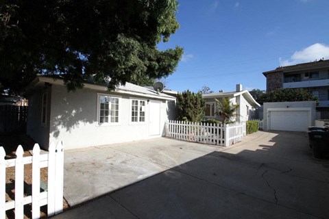 a white house with a driveway and a white fence