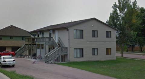 A two-story house with a car parked in front.