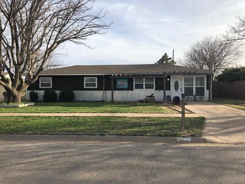 a white and black house with a yard and a tree