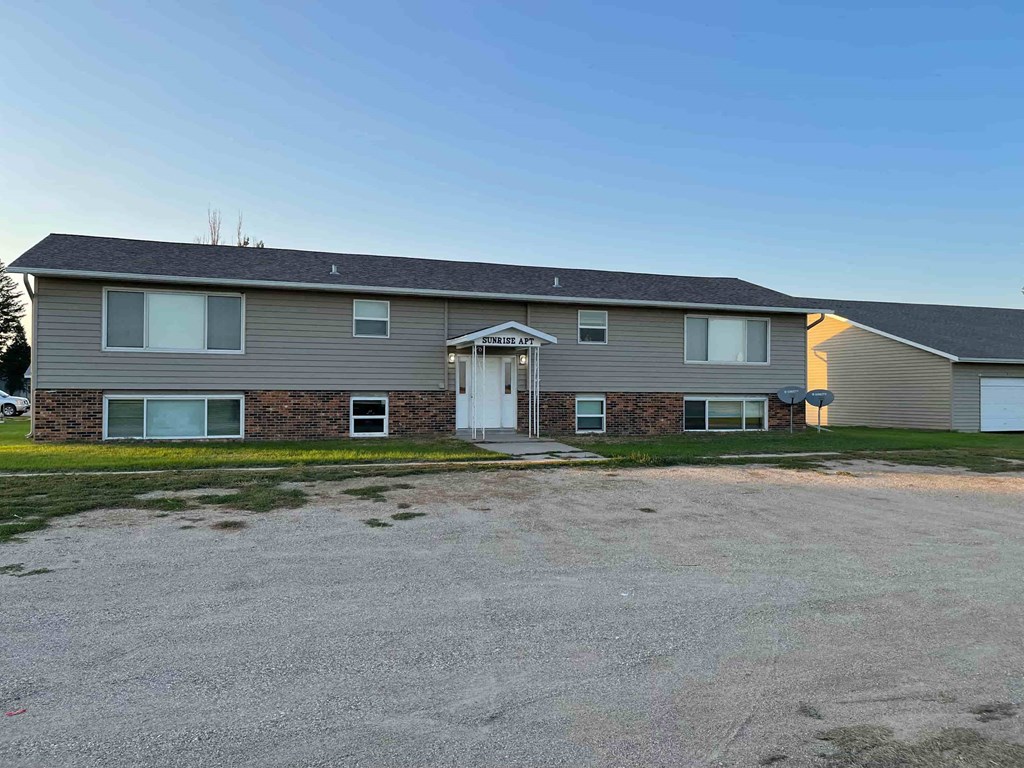 A gravel driveway leads to a two-story house with a garage.