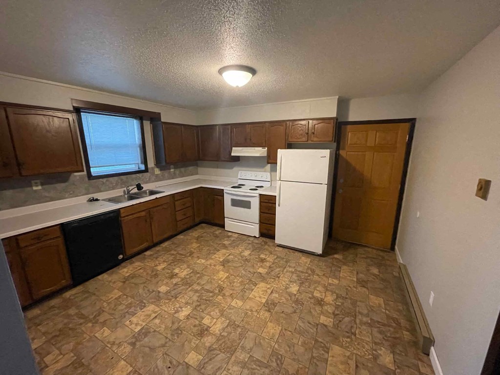 A kitchen with brown cabinets and a white fridge.