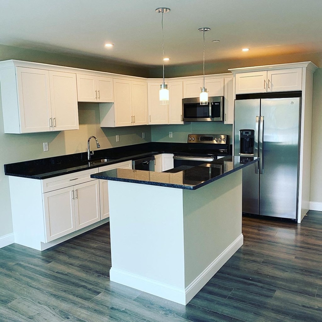 a kitchen with an island and a stainless steel refrigerator