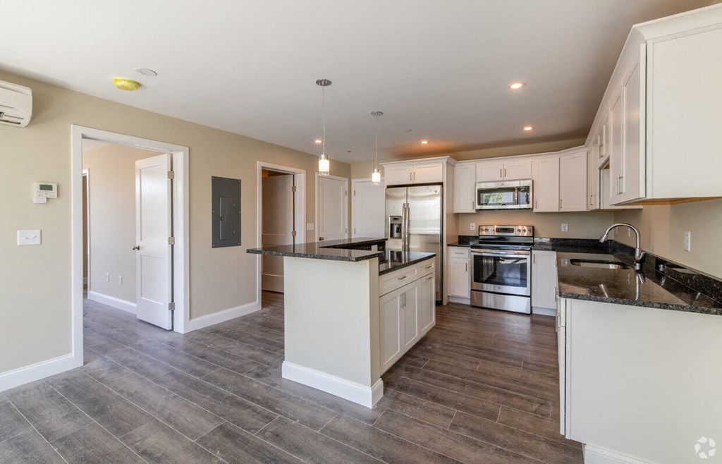 a large kitchen with white cabinets and black counter tops