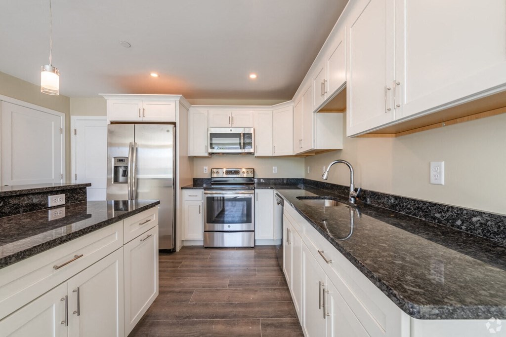 a kitchen with marble counter tops and white cabinets