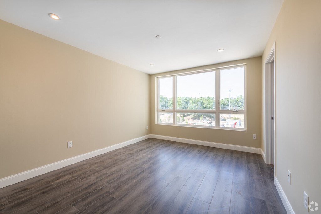 an empty living room with wood floors and a large window