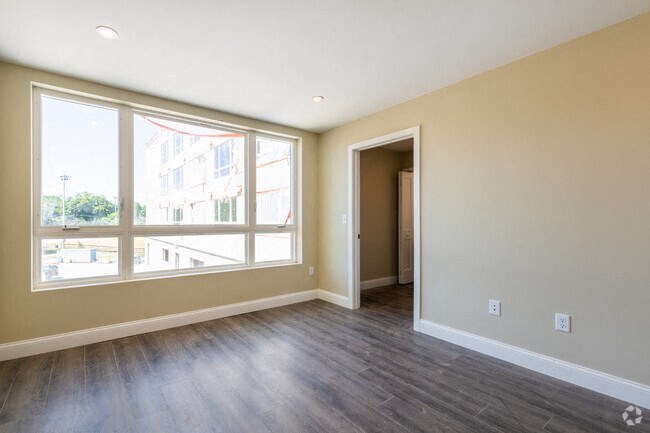 an empty living room with a large window and wood floors