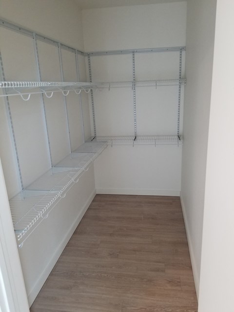 an empty closet with empty shelves and a wood floor