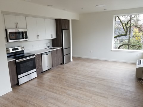 an empty kitchen with white cabinets and a window