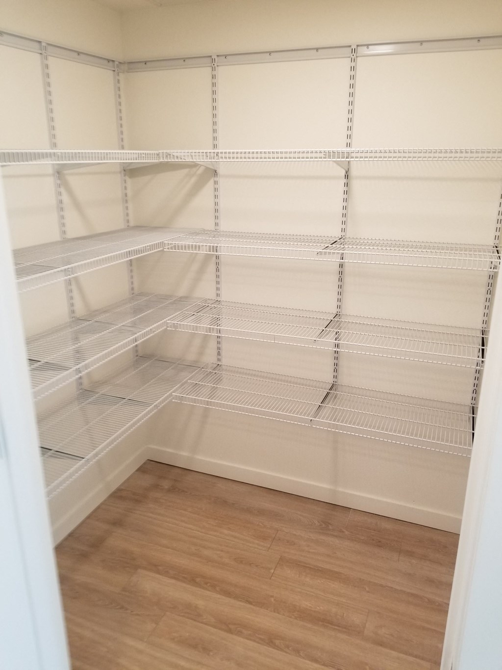 a walk in closet with empty shelves and a wood floor