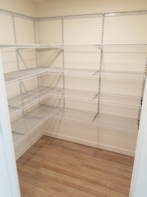 a walk in closet with empty shelves and a wood floor