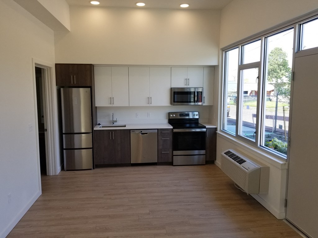 an empty kitchen with a large window and wood flooring