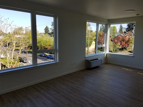 an empty living room with large windows and a wood floor