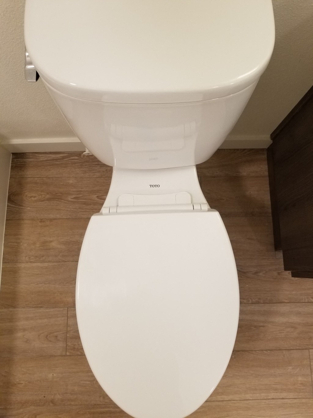 a white toilet in a bathroom with a wooden floor