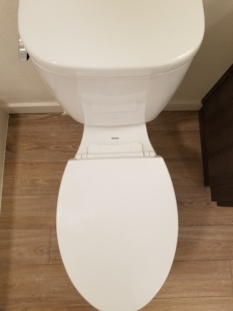 a white toilet in a bathroom with a wooden floor