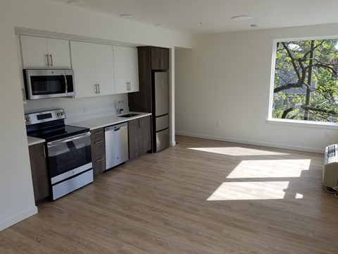 an empty kitchen with white cabinets and a window
