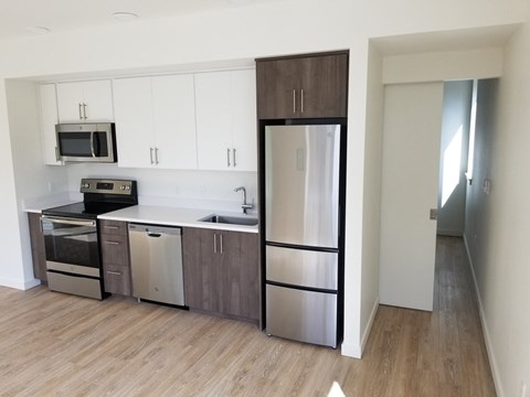 an empty kitchen with stainless steel appliances and white cabinets