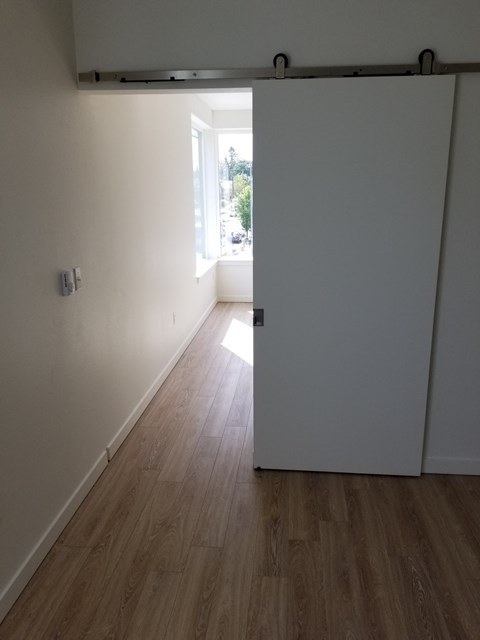 an empty room with a white wall and wooden floors