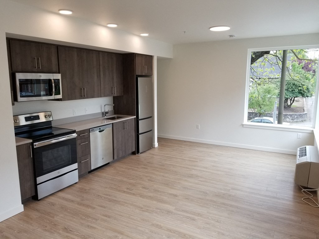 an empty kitchen with a large window and wooden floors