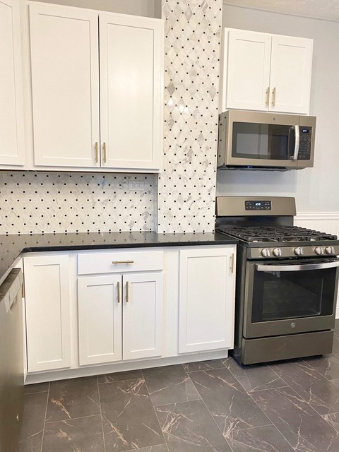 A kitchen with a black stove top oven and white cabinets.