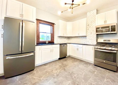 A kitchen with a refrigerator, oven, and microwave.