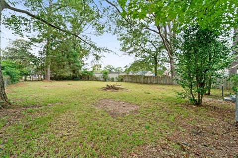 A backyard with a dirt area and a fence.