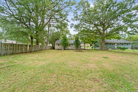 A backyard with a fence and trees.