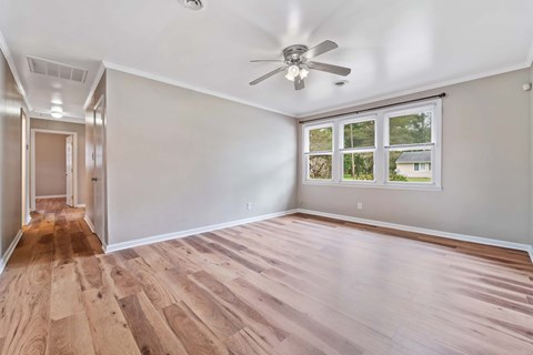 A room with a ceiling fan and wooden flooring.