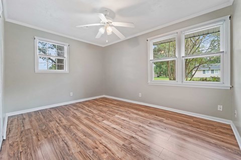 A room with a ceiling fan and two windows.