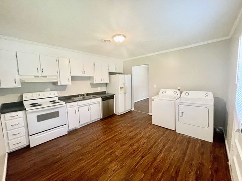 A kitchen with white appliances and wooden floors.