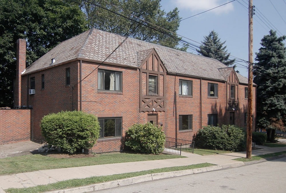 a brick house with a sidewalk in front of it