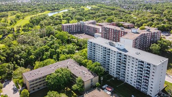an aerial view of a large apartment complex with trees and a river in the background
