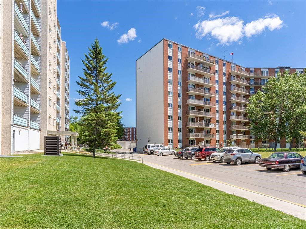 a grassy area next to a parking lot in front of a building