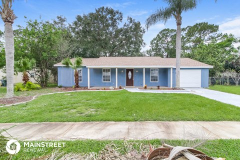a blue house with a lawn and palm trees