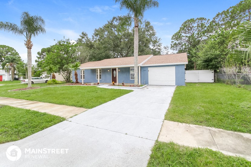 a small blue house with a sidewalk and grass