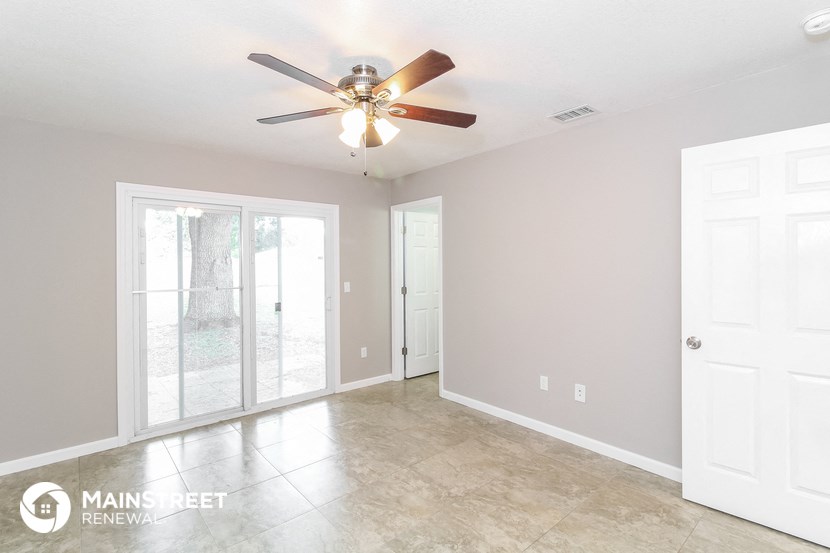 the living room of an empty home with a ceiling fan