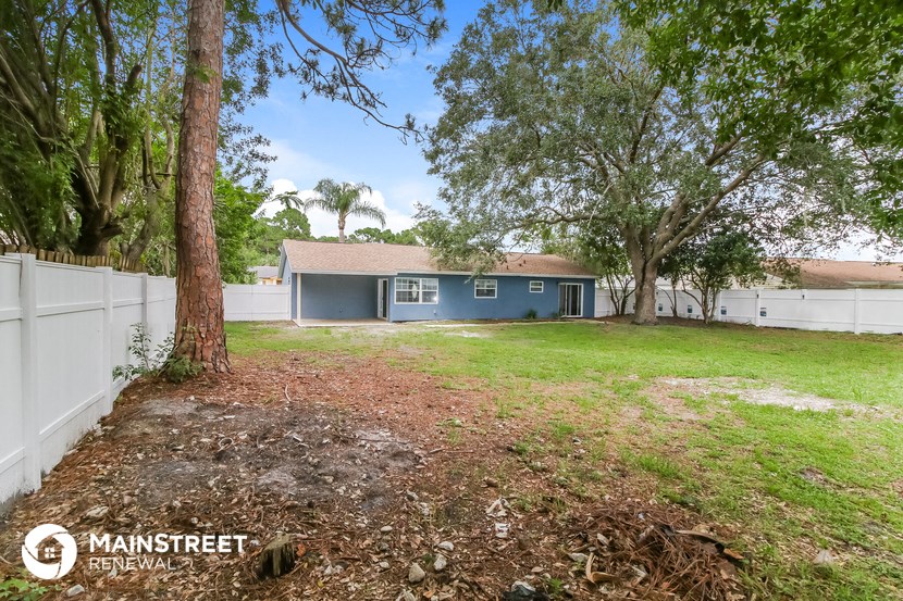 a blue house with a yard and a white fence