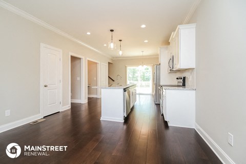 a large kitchen with white cabinets and white appliances and wood floors