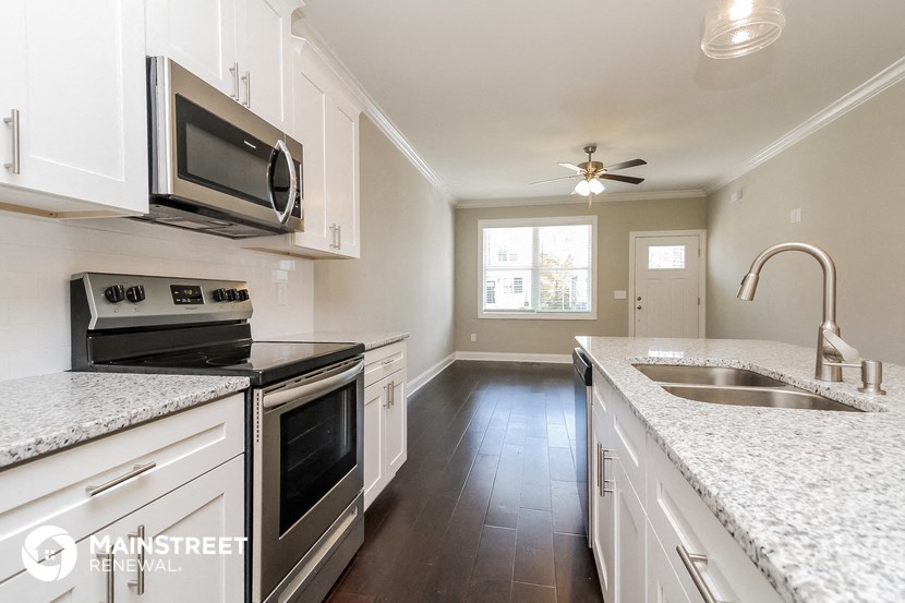 an empty kitchen with marble counter tops and white cabinets