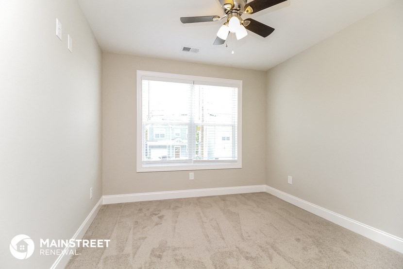 a clean and empty room with a ceiling fan and a window