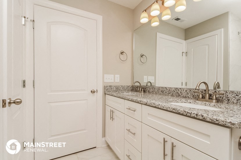 a bathroom with white cabinets and granite counter tops and a sink