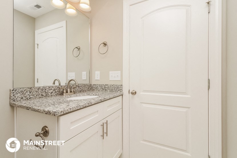a bathroom with white cabinets and granite counter top and a sink