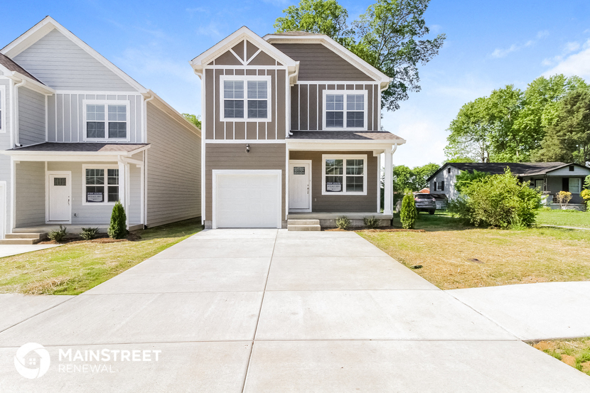 a beige and white house with a driveway in front of it