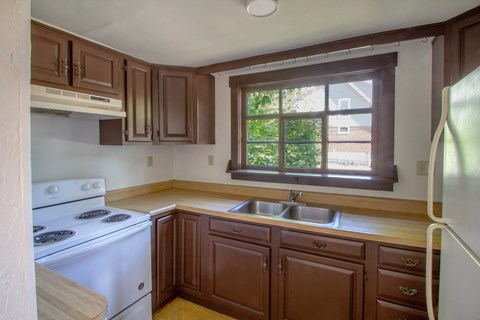 A kitchen with brown cabinets and a white stove.