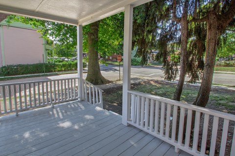 A porch with a white railing and a wooden floor.