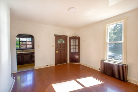 A room with wooden floors and a window with a view of trees.