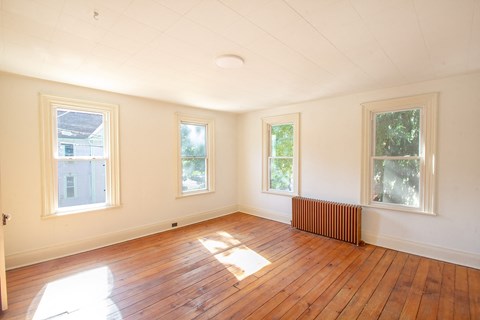 A room with wooden floors and three windows.