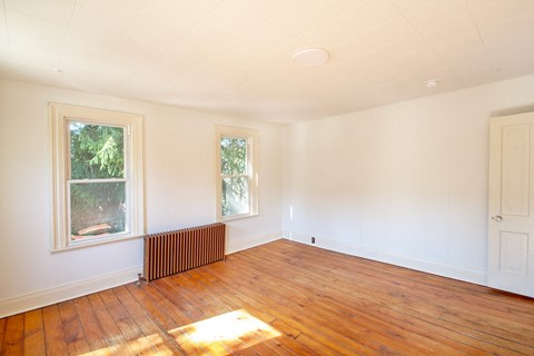 A room with wooden floors and two windows.