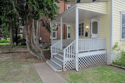 A house with a porch and a tree in front.