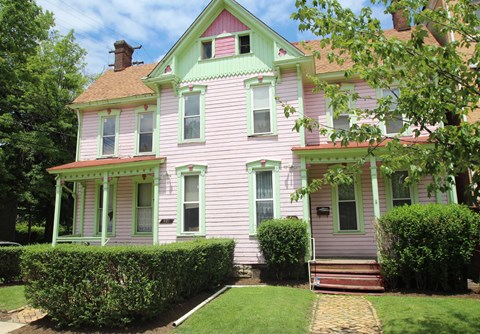 A pink house with green trim and a red door.