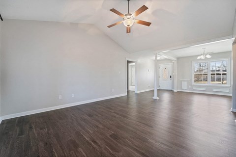 a living room with white walls and a ceiling fan